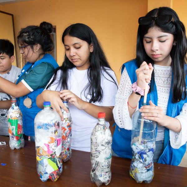 Members of the Interact Club of Abraham Valdelomar in Lima, Peru, fill plastic bottles with plastic scraps as part of the process of building furniture with them. The Interact Club of Abraham Valdelomar, sponsored by the Rotary Club of Lima in Peru, leads a social-emotional wellness workshop and an eco-brick project at a school for younger children in the Independencia district. In the eco-brick project, participants stuff plastic bottles with plastic scraps and use them to build furniture for the school, r
